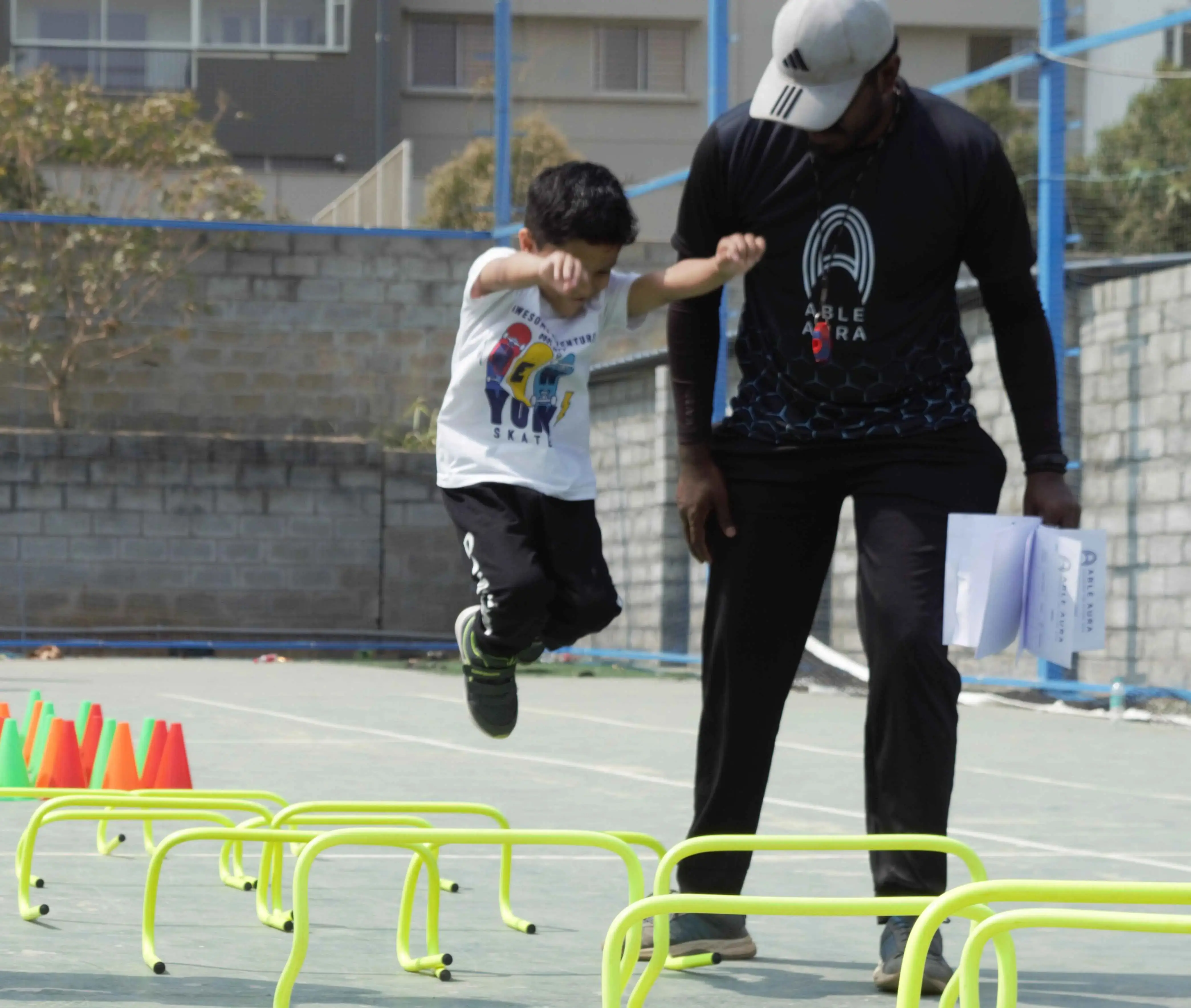 Child doing agility hurdle training with a fitness coach